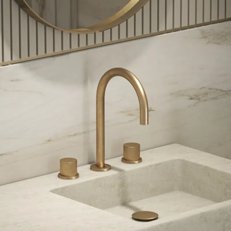 Modern bathroom sink with beige marble countertop and wall, gold faucet, and matching handles beneath round mirror.