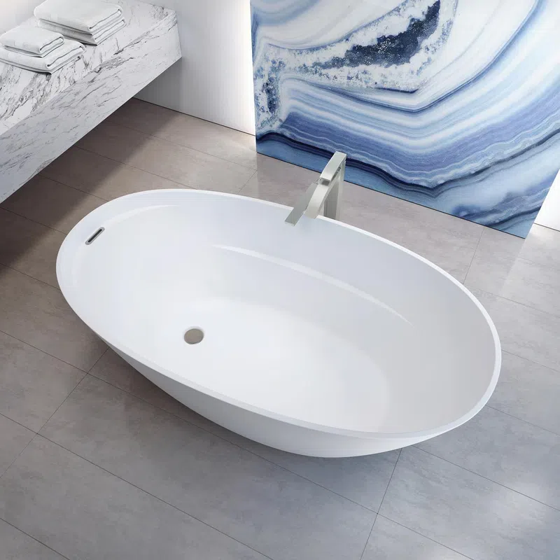 Modern white freestanding oval bathtub with sleek faucet on gray tile floor and blue marble wall art.