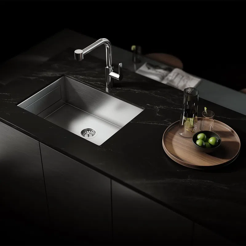 Modern kitchen sink with sleek stainless steel basin and dark marble countertop featuring a wooden tray with glassware and green olives.