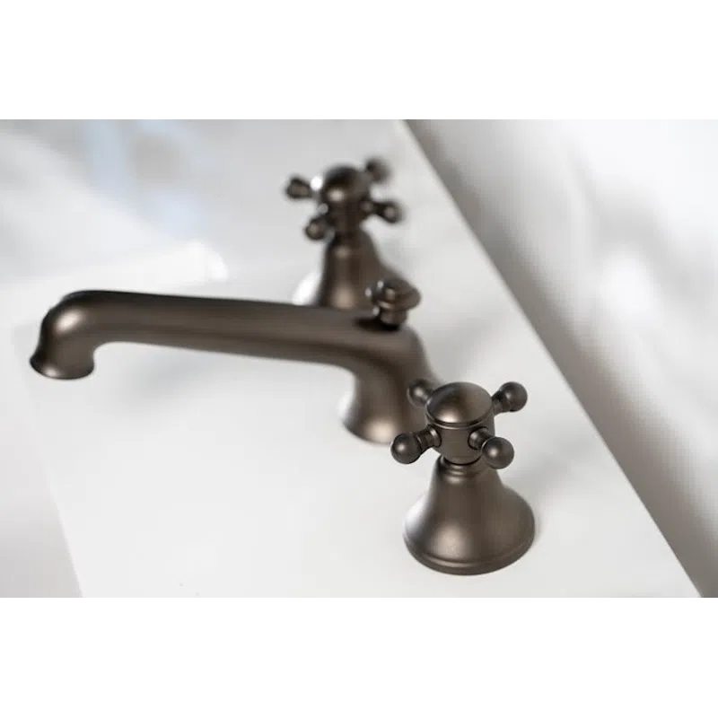 Close-up of a matte black faucet and dual handles on a white bathroom sink countertop.
