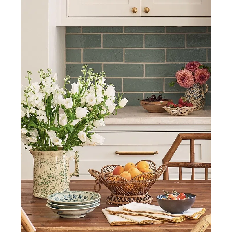 Rustic kitchen table with fresh flowers, fruit bowls, ceramic plates, and vintage kitchen decor.