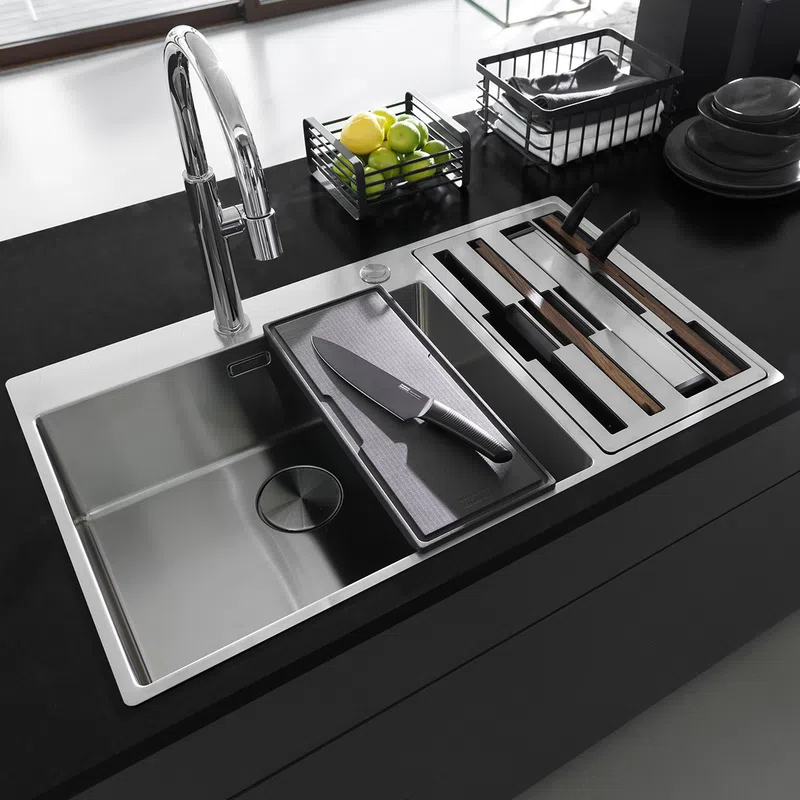 Modern kitchen sink with chrome faucet, integrated cutting board, and organized knife storage on black countertop