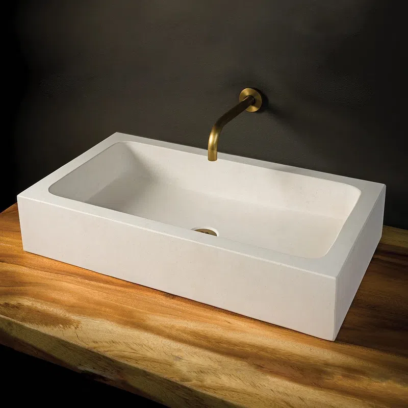 Modern rectangular white bathroom sink with brass wall-mounted faucet on wooden countertop