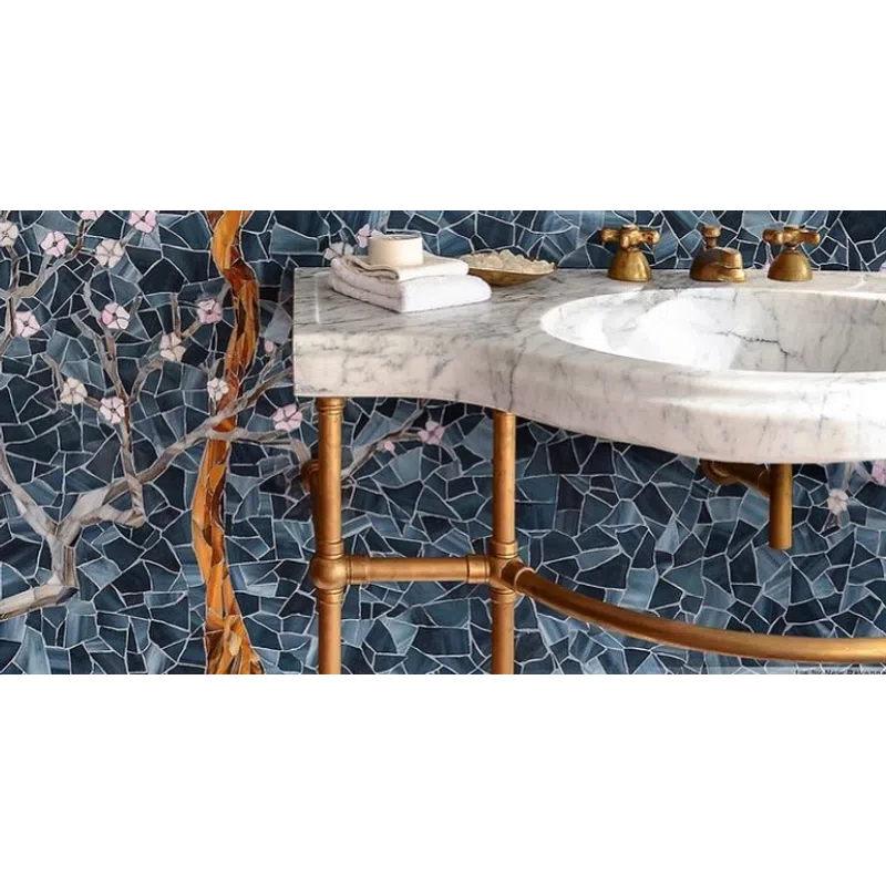 Marble bathroom sink with brass fixtures and floral mosaic tile wall in blue and pink tones.