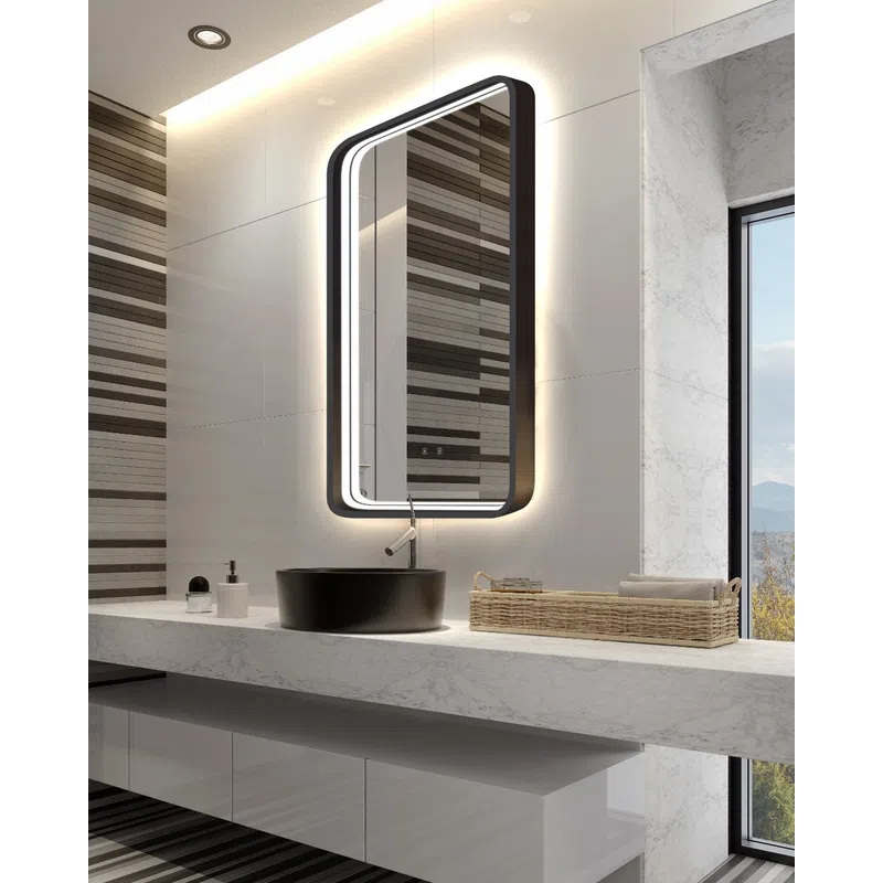 Modern bathroom with illuminated rectangular mirror, black sink, marble countertop, and wicker basket with towels.