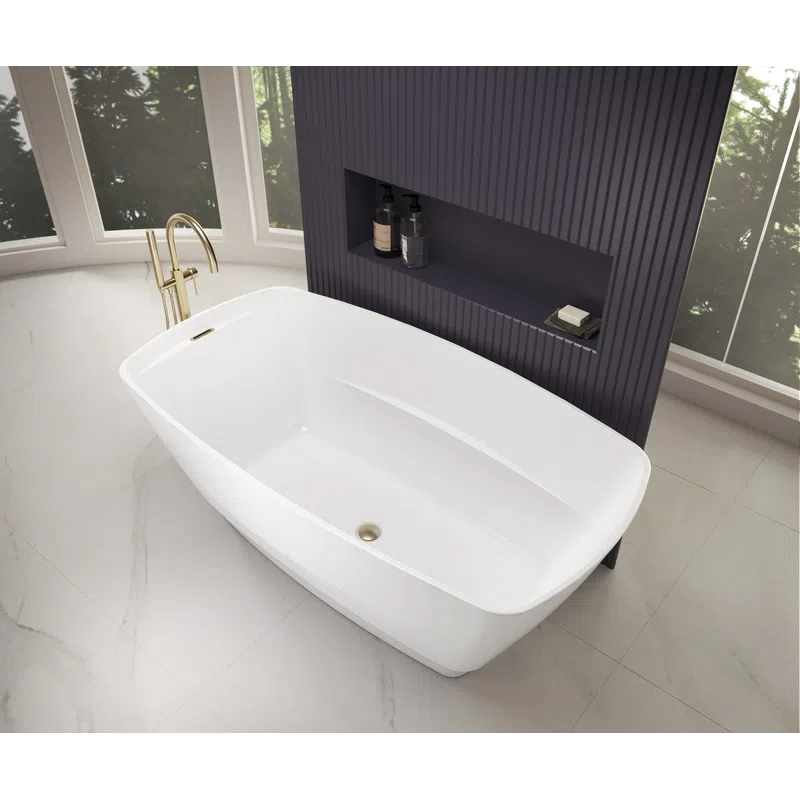 Modern white freestanding bathtub with gold faucet in bright bathroom with purple textured wall niche and large windows.
