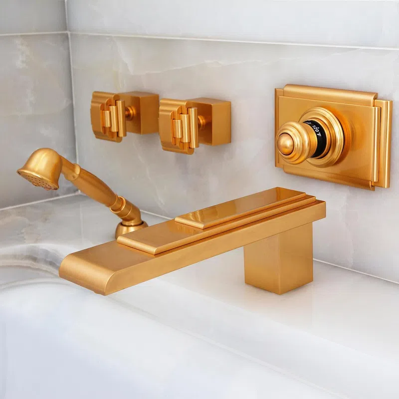 Modern gold matte bathroom faucet set with wall-mounted handles and handheld showerhead on marble tiles.