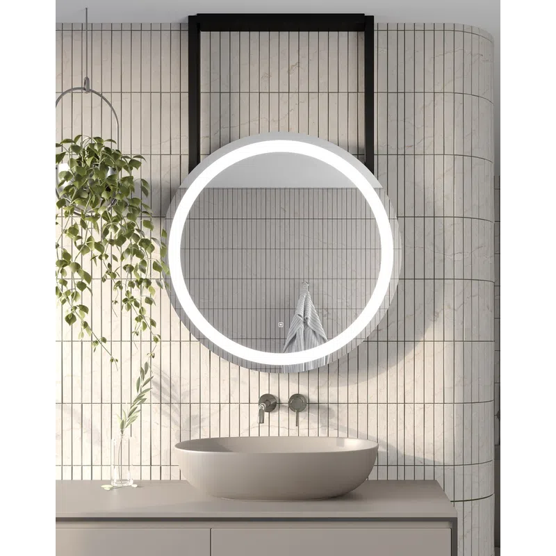 Modern bathroom with a round LED mirror, beige countertop sink, vertical tiled wall, and hanging plant.