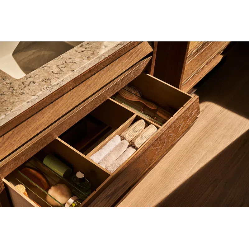 Open wooden bathroom drawer with neatly organized towels, brushes, and toiletries under a marble sink countertop.