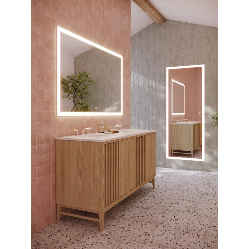 Modern bathroom with wooden vanity, illuminated mirrors, pink and gray tiled walls, terrazzo floor, and green plants.