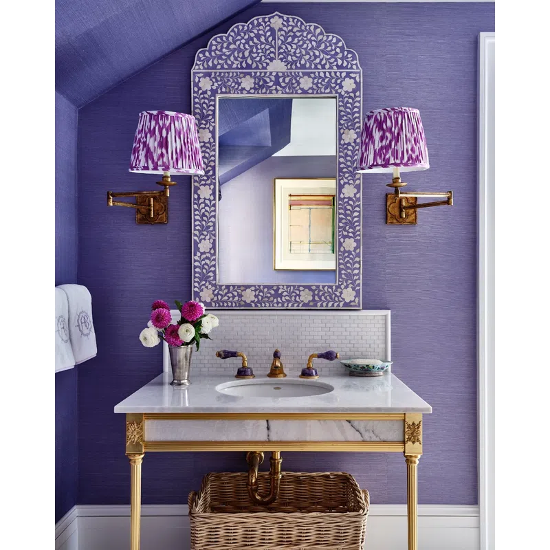 Elegant bathroom vanity with floral patterned mirror, purple walls, gold accents, and decorative lighting.