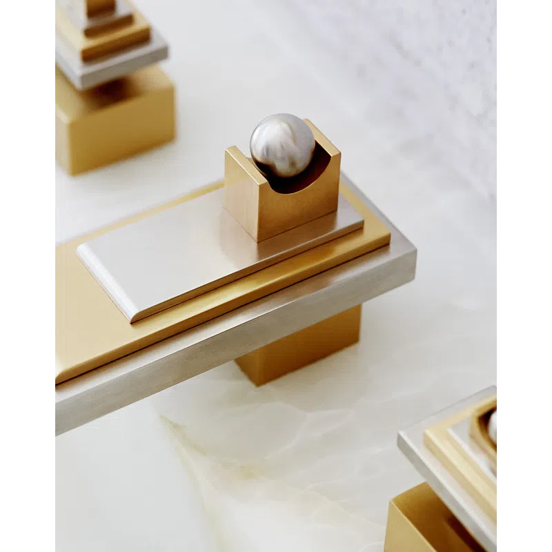 Modern abstract sculpture with gold and silver geometric shapes and a metallic sphere on a white surface.