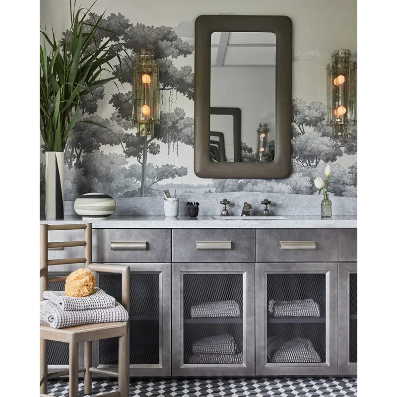 Modern bathroom vanity with gray cabinets, mesh doors, marble countertop, rectangular mirror, and wall mural of trees.