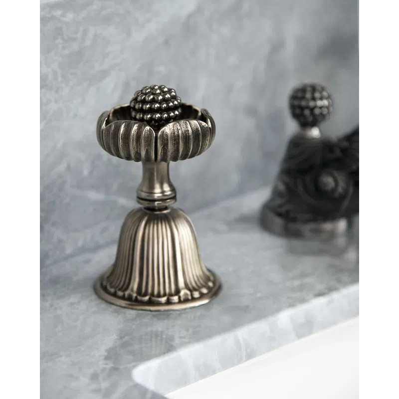 Antique silver doorstop with ornate floral design on marble surface with blurred background.