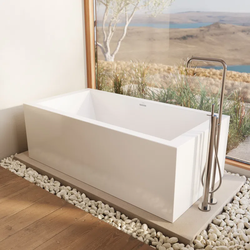 Modern white freestanding bathtub with stainless steel faucet by large window overlooking landscape.