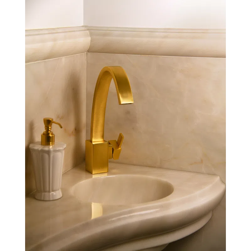 Modern bathroom sink with a curved beige marble countertop and matte gold faucet and soap dispenser.