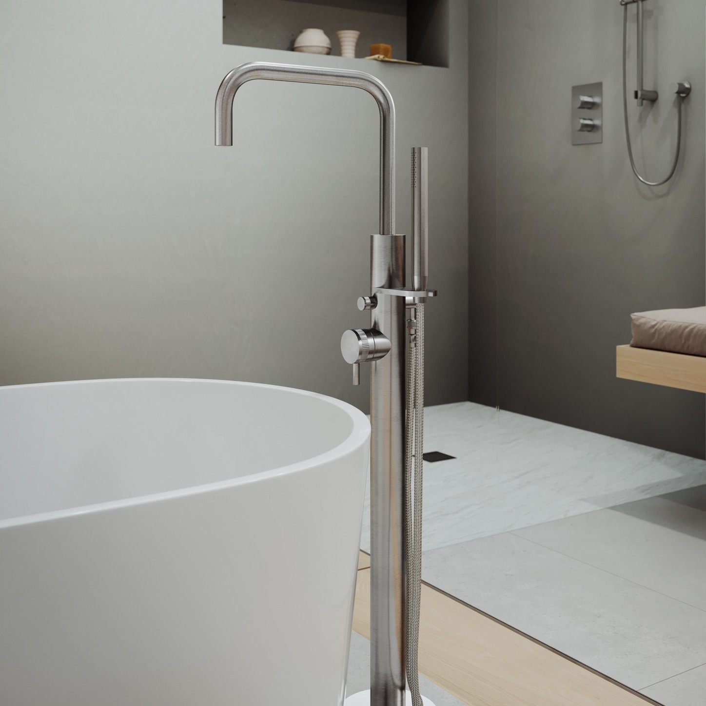Modern bathroom with a freestanding white bathtub and sleek stainless steel floor-mounted faucet and showerhead.
