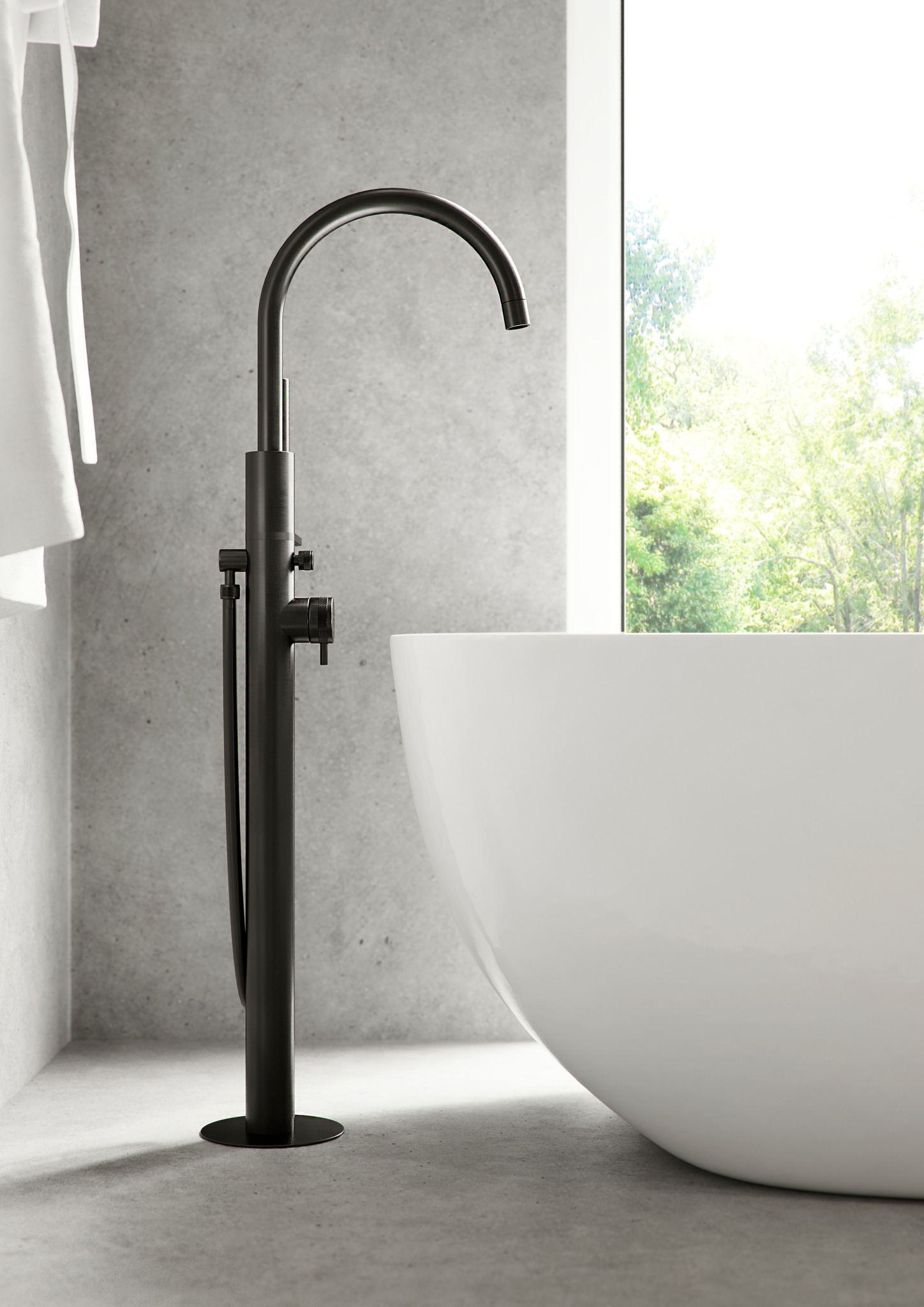 Modern black freestanding tub faucet next to a white bathtub in a minimalist bathroom with concrete walls and natural light.