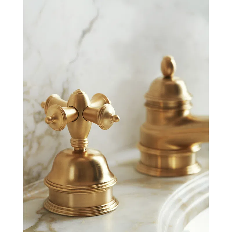 Close-up of elegant gold bathroom faucet handles on marble countertop with soft lighting.