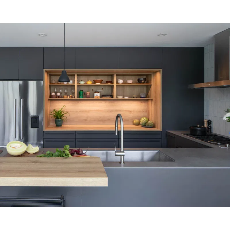 Modern kitchen with grey cabinetry, wooden shelves, stainless steel appliances, and a central island with sink and cutting board.
