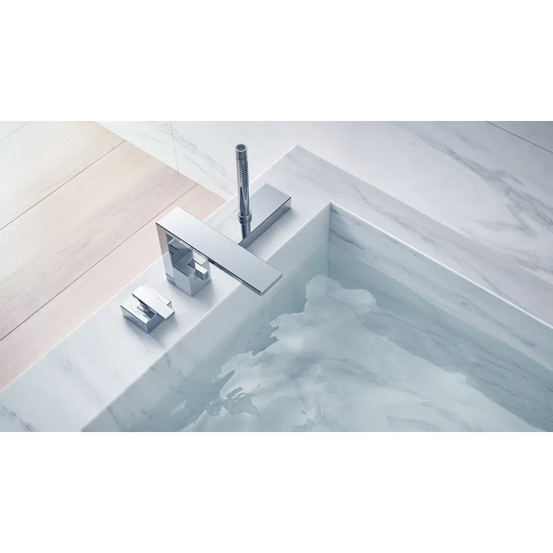 Close-up of modern chrome bathroom faucet and water flowing into a marble bathtub with light wooden flooring.