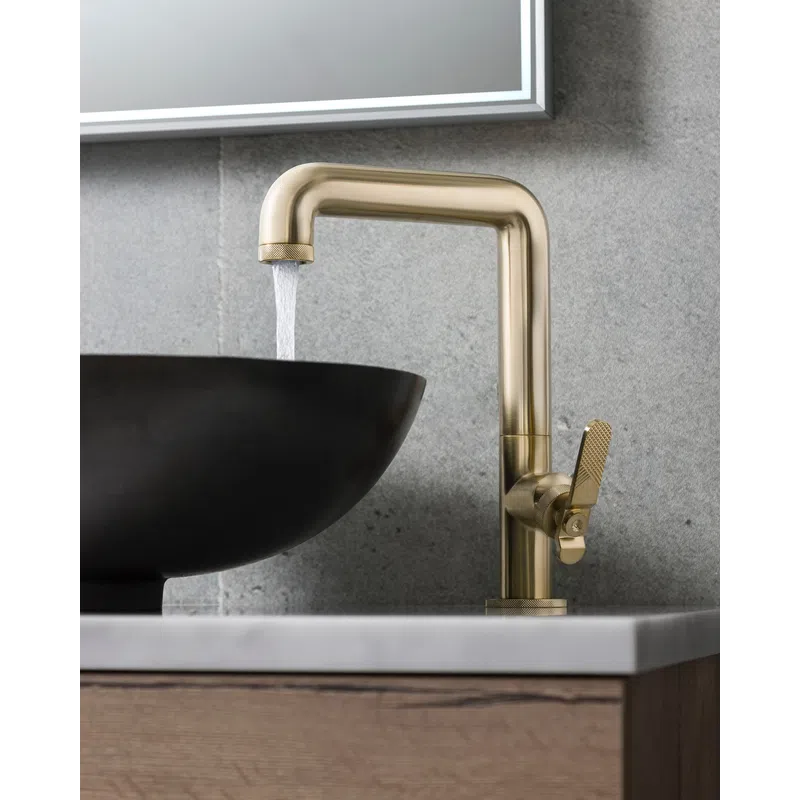 Modern brass faucet with water flowing into a black round vessel sink on a marble countertop.