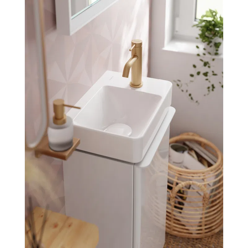 Modern white bathroom sink with gold faucet, soap dispenser, and wicker basket near window and pink wall.