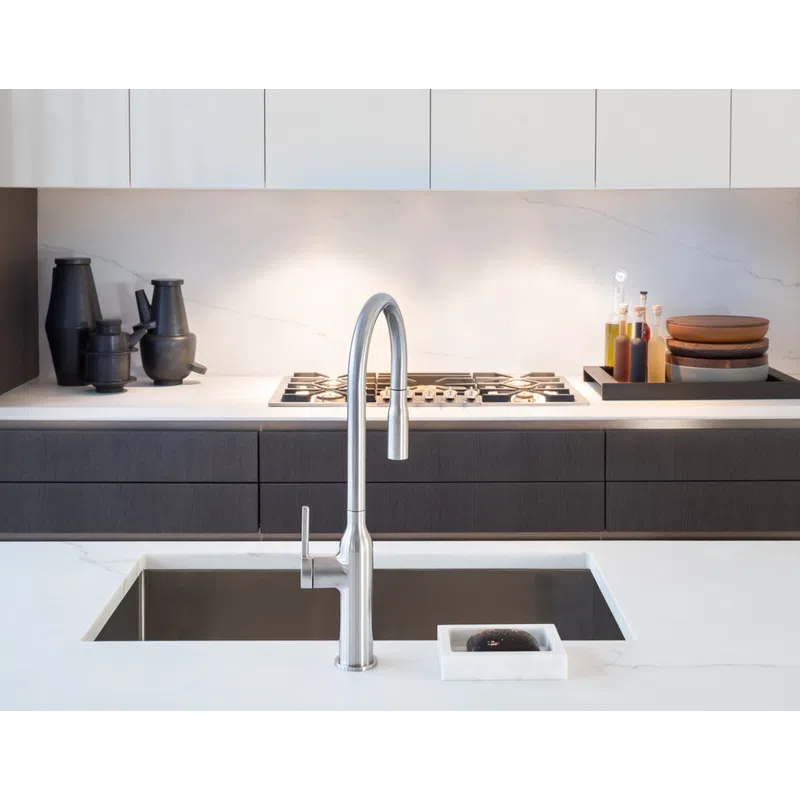 Modern kitchen sink with sleek stainless steel faucet, white marble countertop, and dark cabinetry behind.
