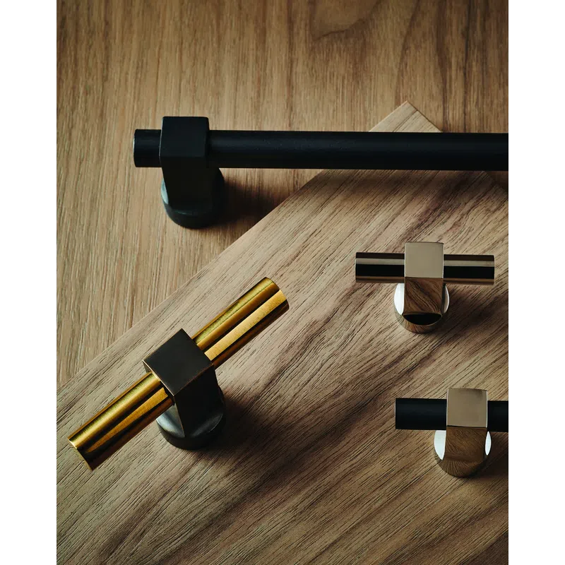 Modern metallic cabinet handles and knobs in black, gold, and chrome finishes displayed on wooden surface.