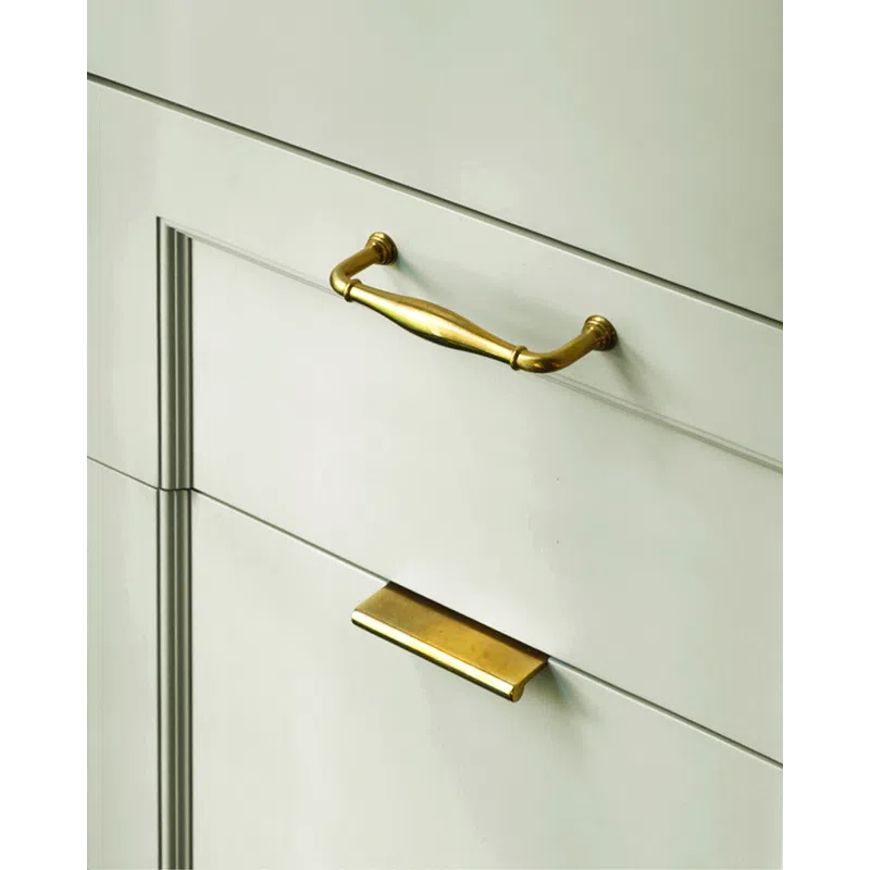 Close-up of white cabinetry with two different styles of gold drawer handles.