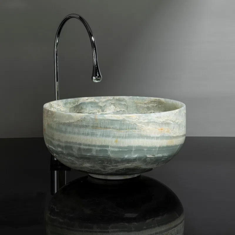 Modern round stone sink with green and white marble patterns paired with a sleek tall chrome faucet.