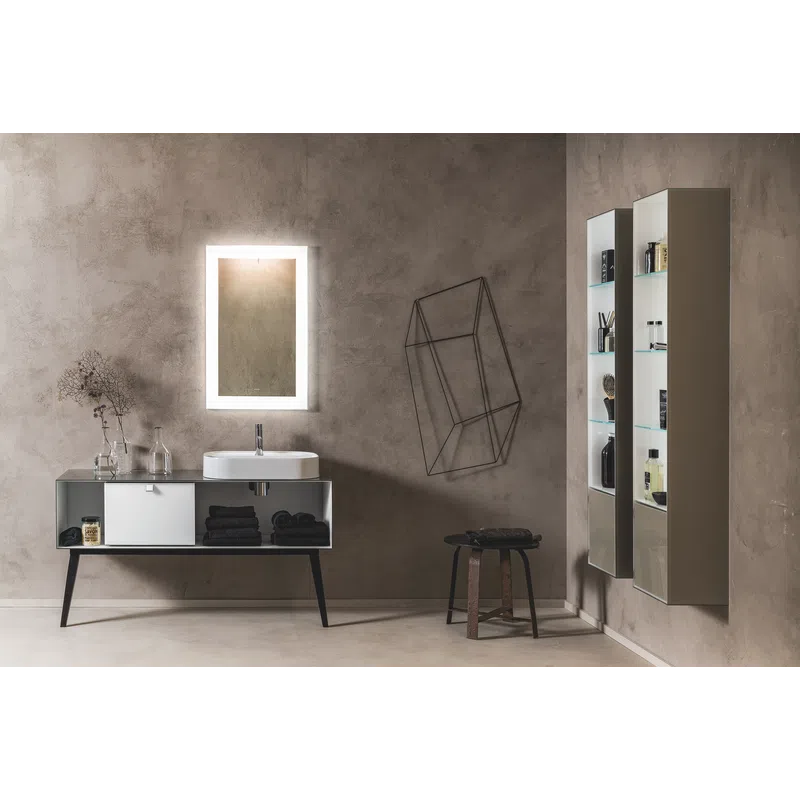 Modern bathroom with glowing rectangular mirror, white sink, minimalist storage, and geometric wall decor on gray walls.