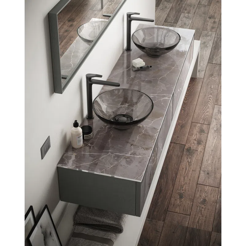 Modern bathroom vanity with double black glass vessel sinks, marble countertop, and wood flooring.