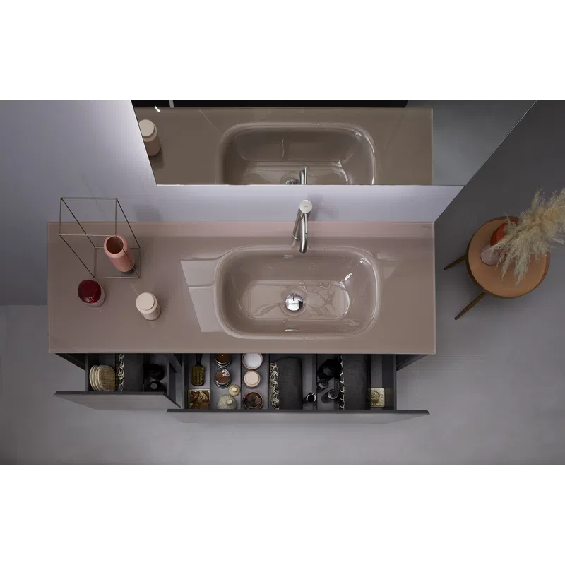 Modern bathroom sink with organized drawer storage and decorative items on the countertop and side table.