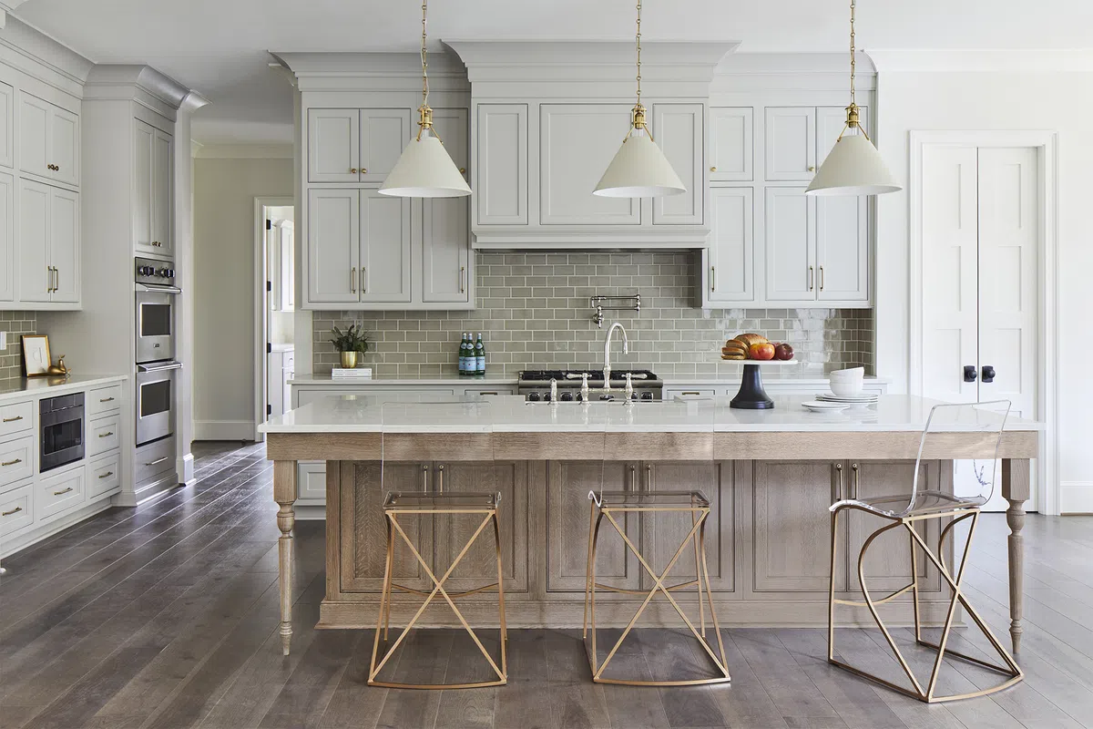 Bright modern kitchen with white cabinetry, large island with wooden base, and three unique metal stools.