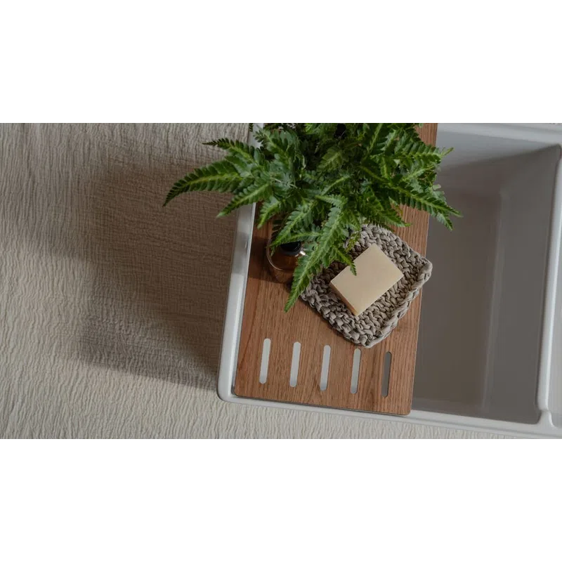 Top view of a bathtub with wooden tray holding a green fern plant and a soap bar on a knitted holder.