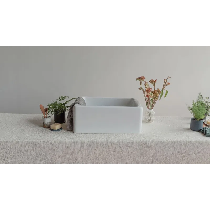 Modern white rectangular sink on a textured tablecloth with plants and dried flowers on both sides