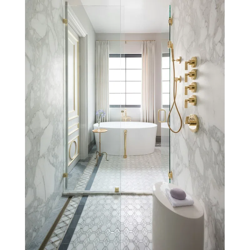 Luxurious bathroom with marble walls, gold fixtures, freestanding tub, and glass-enclosed shower with patterned floor tiles.