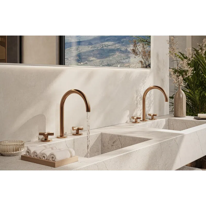 Modern double marble sink with gold faucets, decorative towels, and plants in a bright bathroom setting.