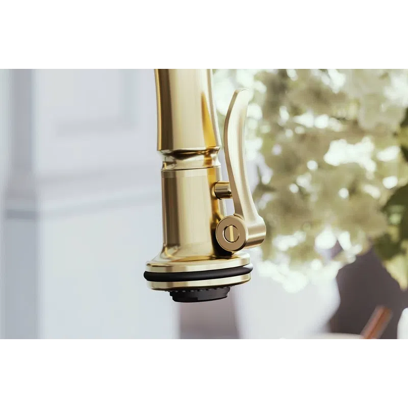 Close-up of a modern gold kitchen faucet with lever handle against blurred white flowers background