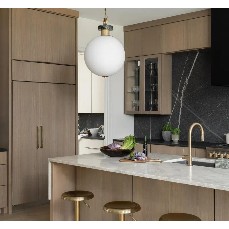 Modern kitchen with light wood cabinets, gold bar stools, marble island, black backsplash, and pendant light