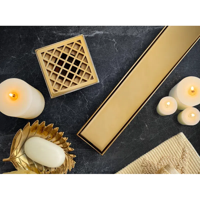 Luxurious gold bathroom accessories with white candles, soap on a leaf dish, sponge, and folded towels on black marble.