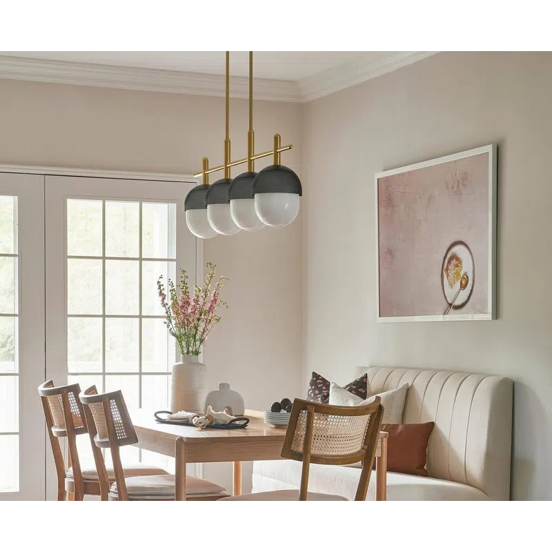Modern dining room with wooden table, cane-back chairs, beige banquette seating, pendant lights, and floral centerpiece.