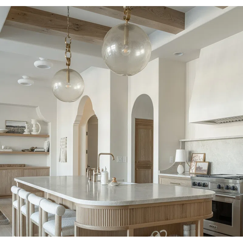 Modern kitchen with wooden island, marble countertop, pendant lights, and light wood cabinetry in neutral tones.