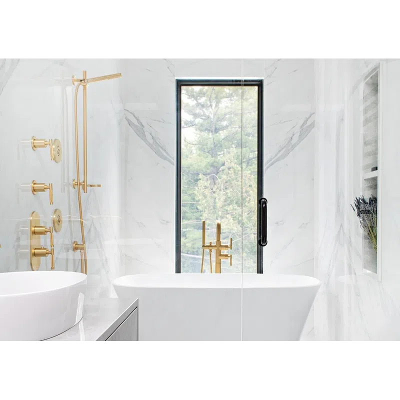 Modern white marble bathroom with freestanding tub, gold fixtures, large window, and vessel sink on gray vanity.