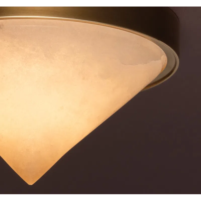 Close-up of a warm glowing conical ceiling light fixture with brass trim against a dark background.