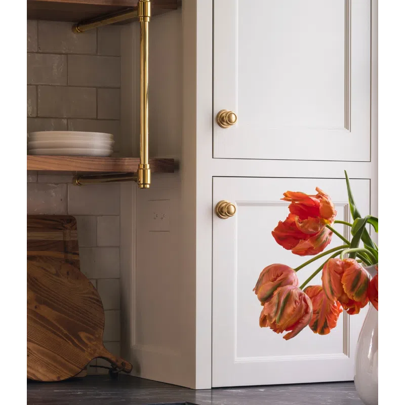 Modern kitchen corner with white cabinets, dark countertops, brass handles, wooden cutting boards, and orange tulips.