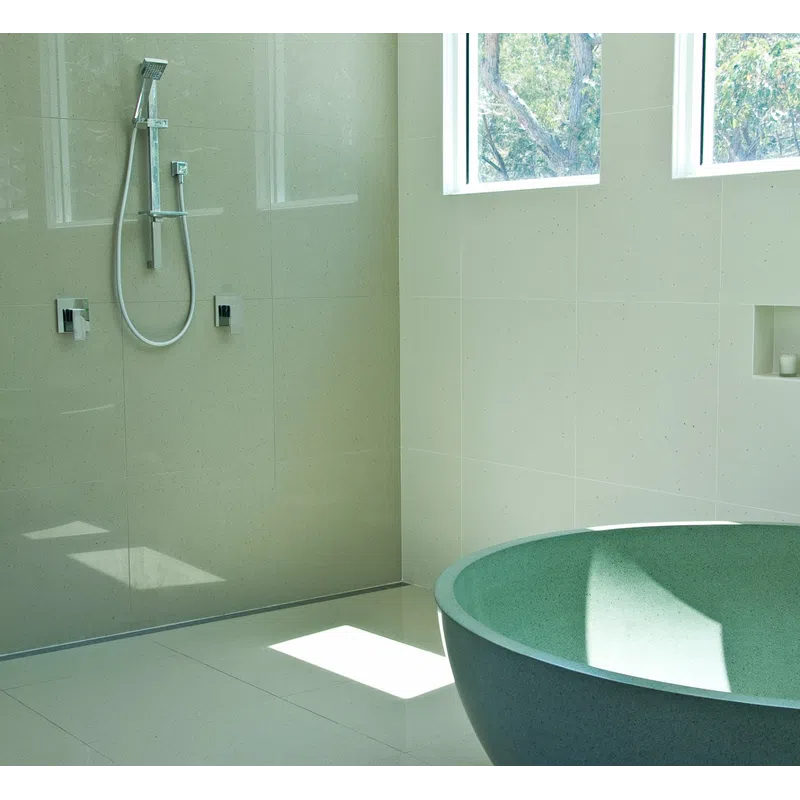 Bright modern bathroom with a green freestanding tub, wall-mounted shower, large windows, and beige tile walls.