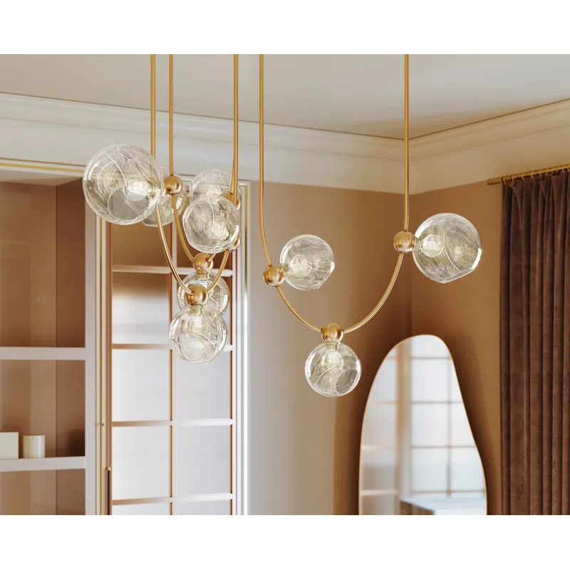 Modern kitchen with marble island, gold spherical pendant lights, floral centerpiece, and tall curved mirror.