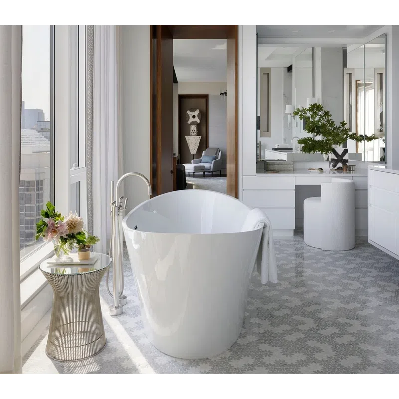 Modern bathroom with freestanding white tub, floral side table, large mirror, and city view through windows